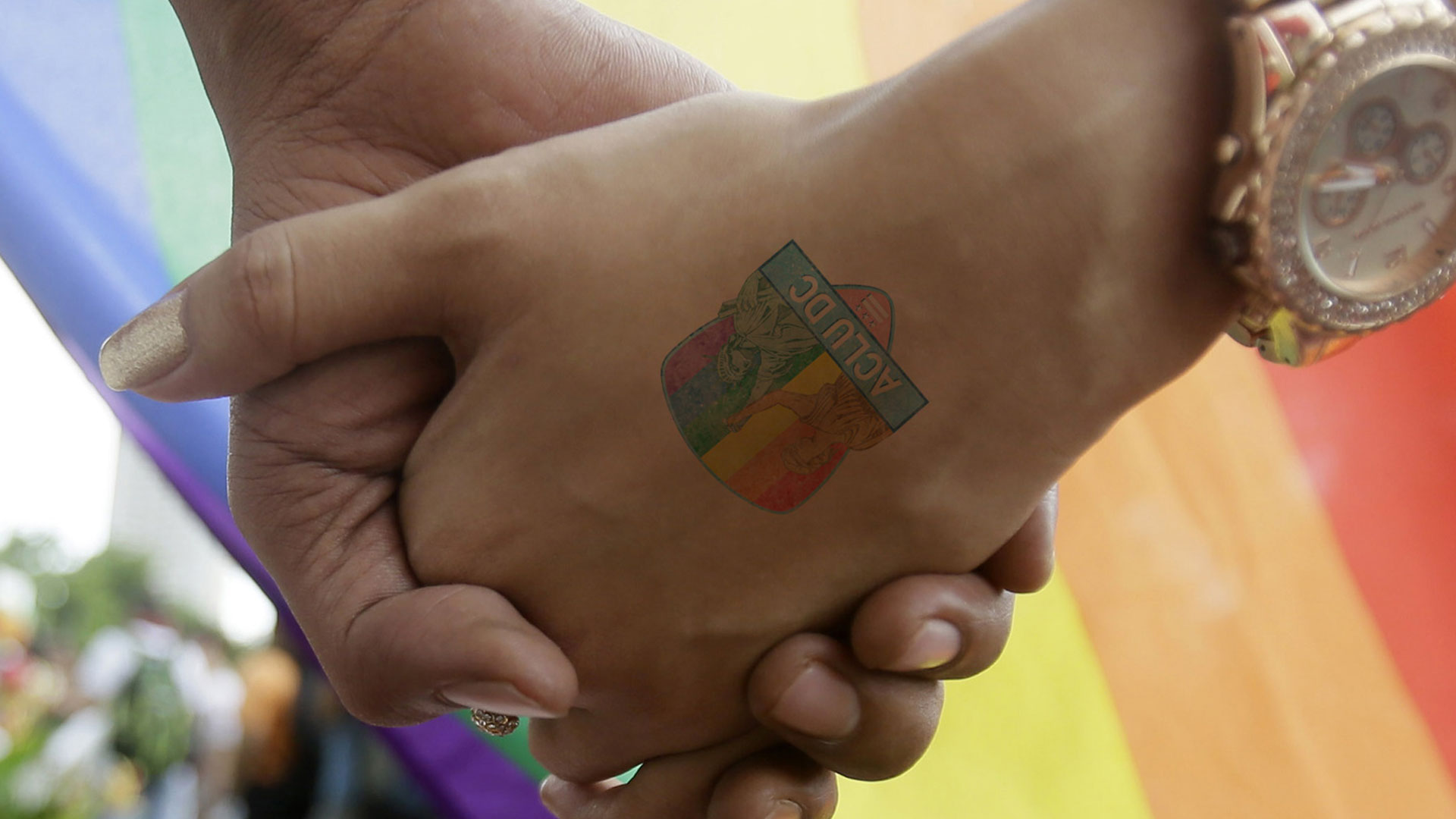 Close up of women holding hands. One of which has the ACLU DC temporary tattoo we created as part of the branding